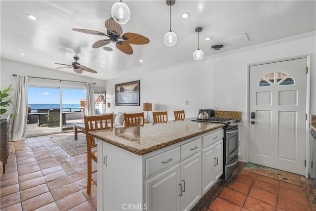 kitchen with a water view, pendant lighting, a kitchen bar, white cabinets, and stainless steel range with gas stovetop