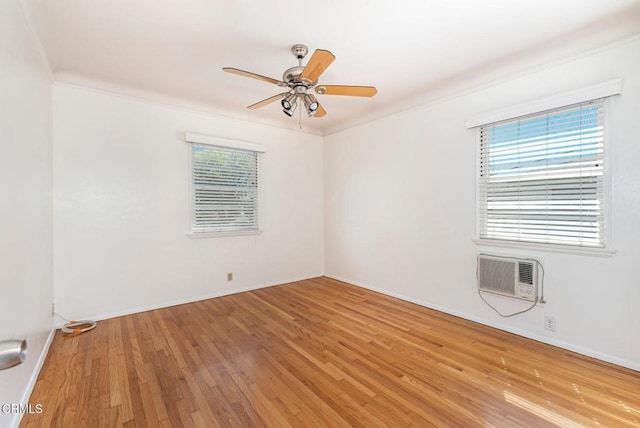 spare room with a wall mounted AC, ornamental molding, a healthy amount of sunlight, and hardwood / wood-style flooring