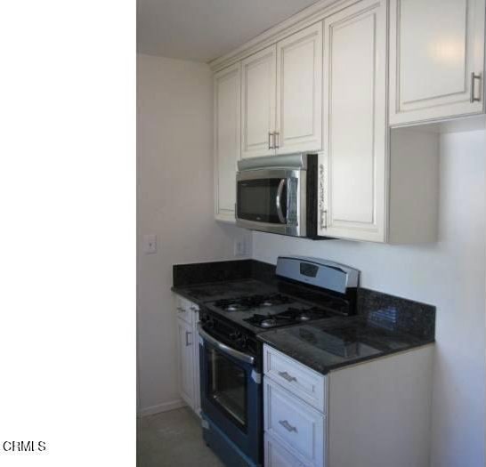 kitchen featuring gas range and white cabinets