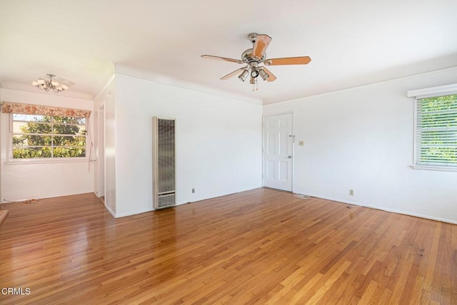 spare room with ceiling fan with notable chandelier, hardwood / wood-style flooring, and a wealth of natural light