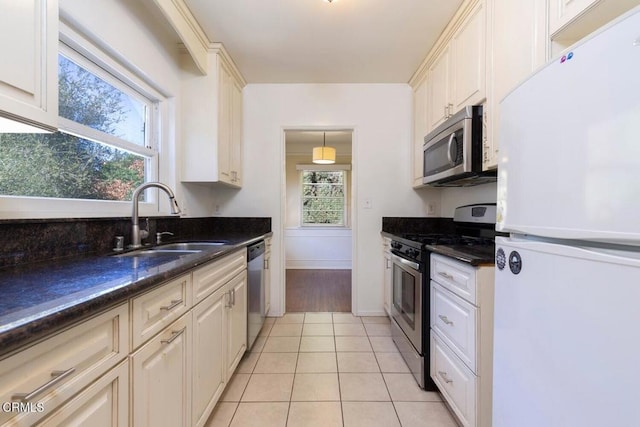 kitchen with a wealth of natural light, sink, light tile patterned flooring, and stainless steel appliances