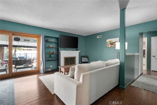 living room featuring a textured ceiling, dark hardwood / wood-style flooring, and a brick fireplace