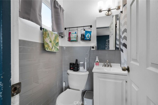 bathroom featuring vanity, toilet, and tile walls