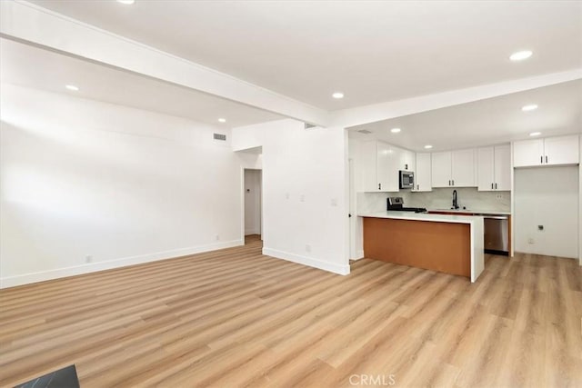 kitchen with white cabinetry, beamed ceiling, light hardwood / wood-style floors, kitchen peninsula, and stainless steel appliances