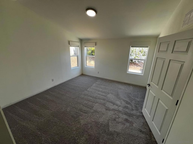 spare room with dark carpet