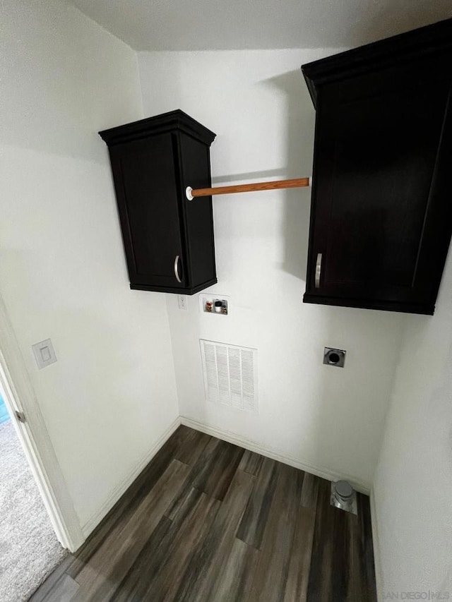 clothes washing area featuring electric dryer hookup, dark hardwood / wood-style flooring, and cabinets