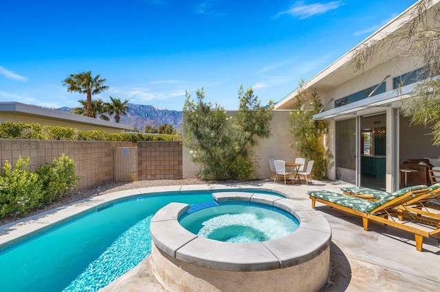 view of pool featuring a mountain view, a patio area, and an in ground hot tub