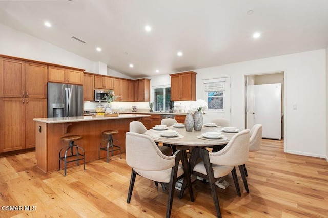 dining space featuring vaulted ceiling and light hardwood / wood-style flooring