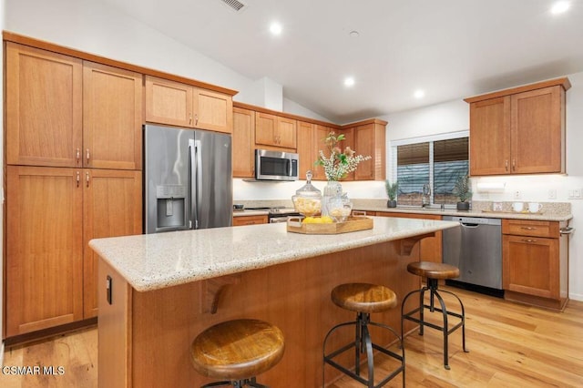 kitchen with lofted ceiling, stainless steel appliances, a kitchen breakfast bar, and a kitchen island