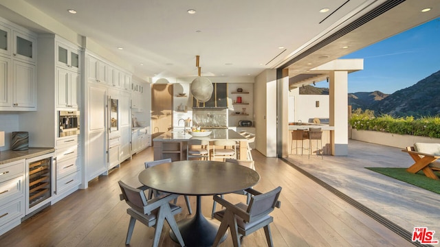 dining area with hardwood / wood-style floors, a mountain view, and beverage cooler