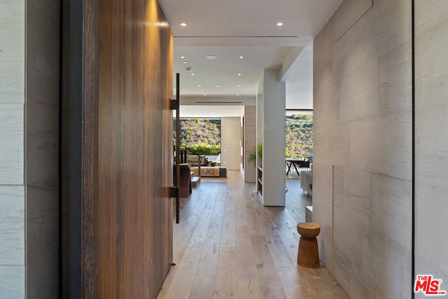 hallway with floor to ceiling windows and light hardwood / wood-style floors