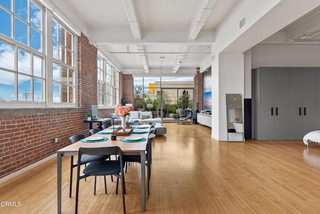 dining space with rail lighting, ceiling fan, light hardwood / wood-style floors, beam ceiling, and brick wall