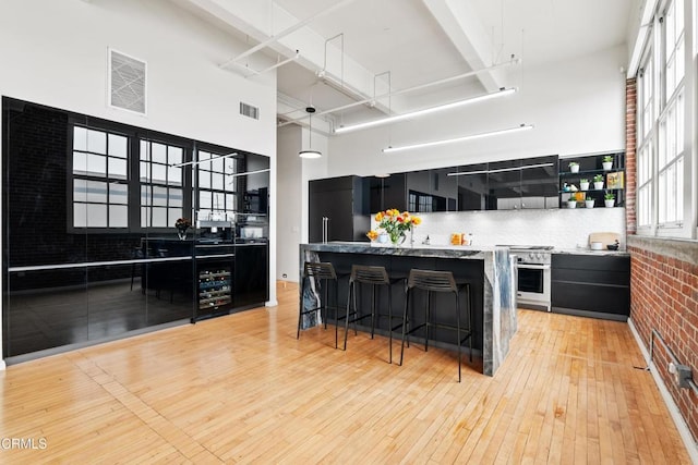 kitchen with stainless steel oven, a high ceiling, built in refrigerator, light hardwood / wood-style floors, and a breakfast bar area