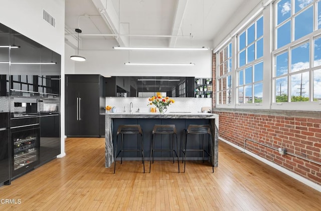 kitchen with built in fridge, light hardwood / wood-style floors, and brick wall