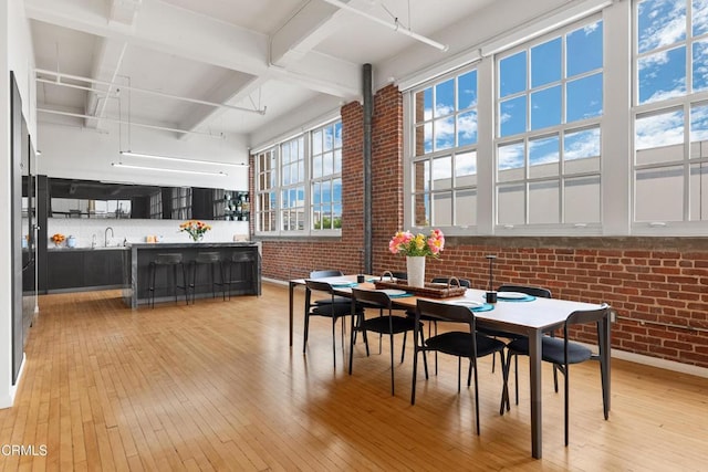 dining room with light wood-type flooring and brick wall