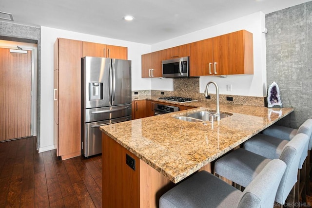 kitchen featuring kitchen peninsula, sink, stainless steel appliances, and dark hardwood / wood-style flooring