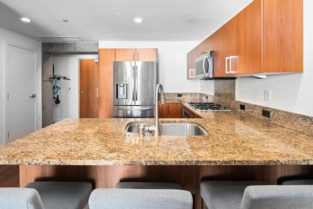 kitchen with kitchen peninsula, a breakfast bar, stainless steel appliances, and sink