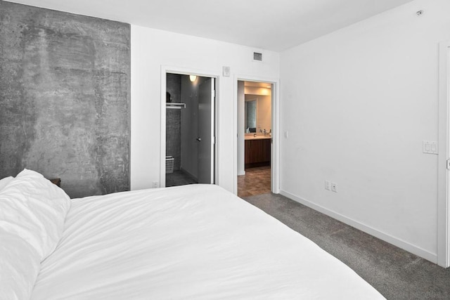 bedroom with ensuite bath and dark carpet