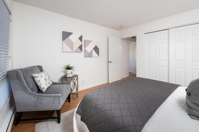 bedroom featuring a closet, a baseboard radiator, and hardwood / wood-style flooring