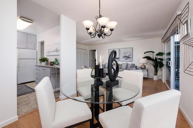 dining area featuring a textured ceiling, light hardwood / wood-style floors, and a notable chandelier