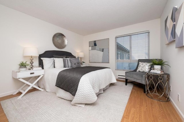 bedroom with a baseboard radiator and hardwood / wood-style flooring