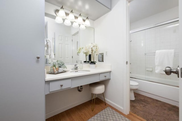 full bathroom with toilet, sink, bath / shower combo with glass door, and hardwood / wood-style flooring