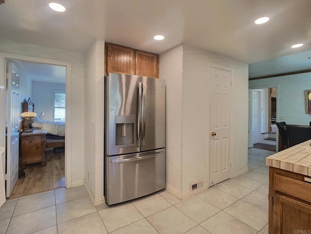 kitchen with tile countertops, stainless steel fridge, and light tile patterned flooring