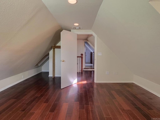 additional living space with a textured ceiling, dark wood-type flooring, and lofted ceiling