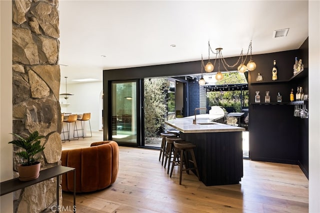 kitchen with light wood-type flooring, decorative light fixtures, a wealth of natural light, and sink