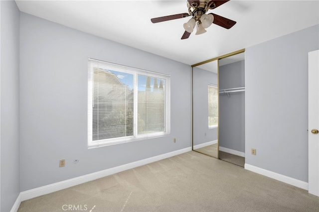 unfurnished bedroom featuring ceiling fan, a closet, and light carpet