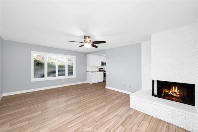 unfurnished living room with ceiling fan, a fireplace, and light wood-type flooring