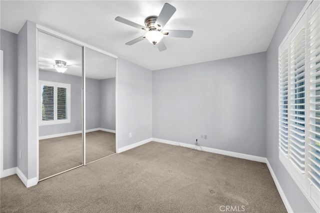 unfurnished bedroom featuring multiple windows, ceiling fan, a closet, and carpet