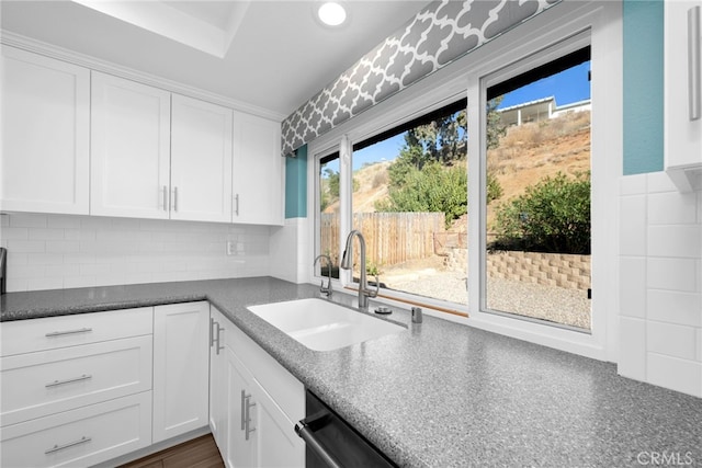 kitchen featuring tasteful backsplash, dishwasher, sink, and white cabinets