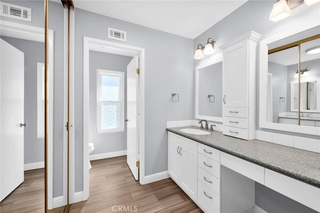 bathroom featuring toilet, vanity, and hardwood / wood-style flooring