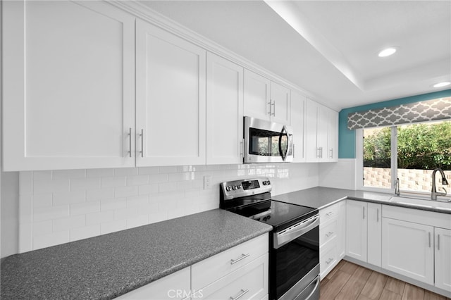 kitchen featuring sink, light wood-type flooring, white cabinetry, and stainless steel appliances