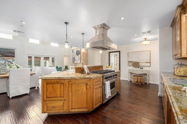 kitchen with a center island, dark hardwood / wood-style flooring, high end stove, extractor fan, and decorative light fixtures