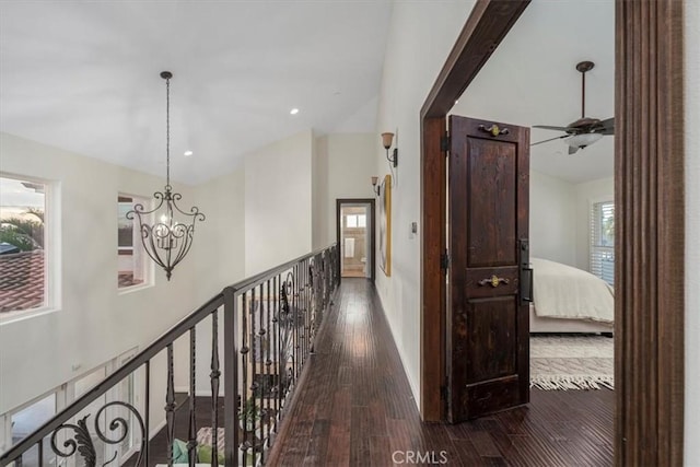 hallway with dark hardwood / wood-style floors and a notable chandelier