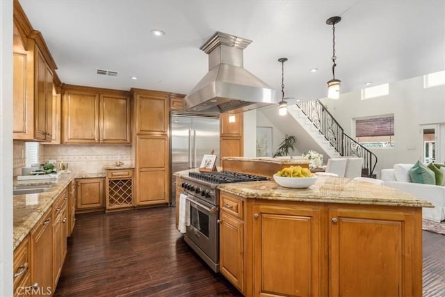 kitchen with dark wood-type flooring, ventilation hood, decorative light fixtures, high quality appliances, and a kitchen island