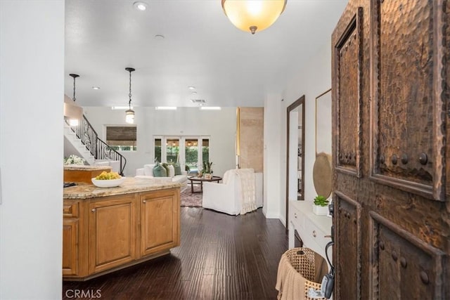 kitchen with pendant lighting, light stone counters, french doors, and dark wood-type flooring