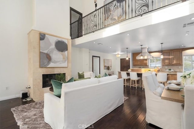 living room with a fireplace, dark wood-type flooring, and a high ceiling