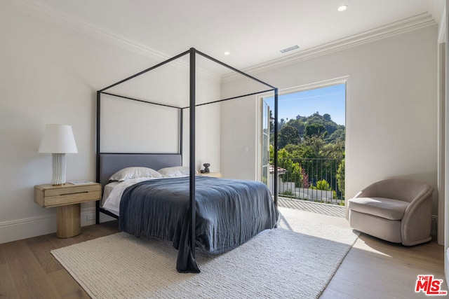 bedroom with wood-type flooring, crown molding, and access to outside