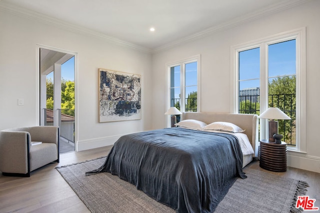 bedroom featuring multiple windows, crown molding, and light wood-type flooring