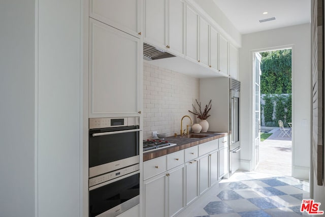 kitchen featuring decorative backsplash, white cabinetry, and sink