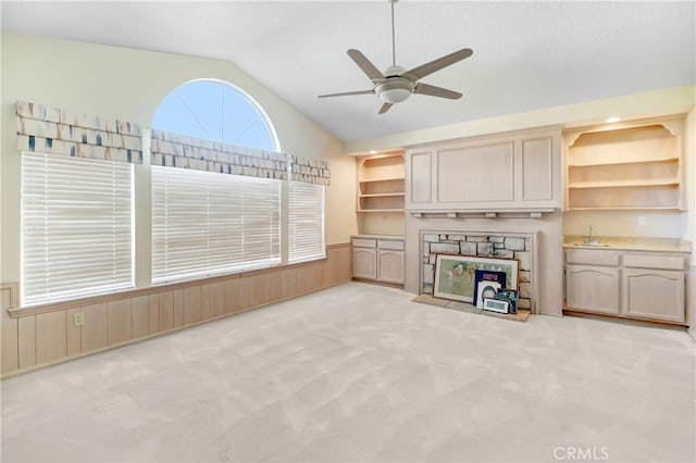 unfurnished living room featuring light carpet, sink, ceiling fan, and lofted ceiling