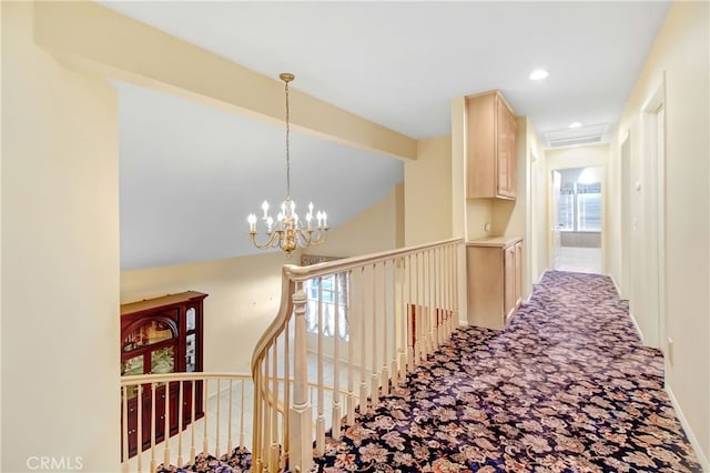 hallway with carpet floors and an inviting chandelier