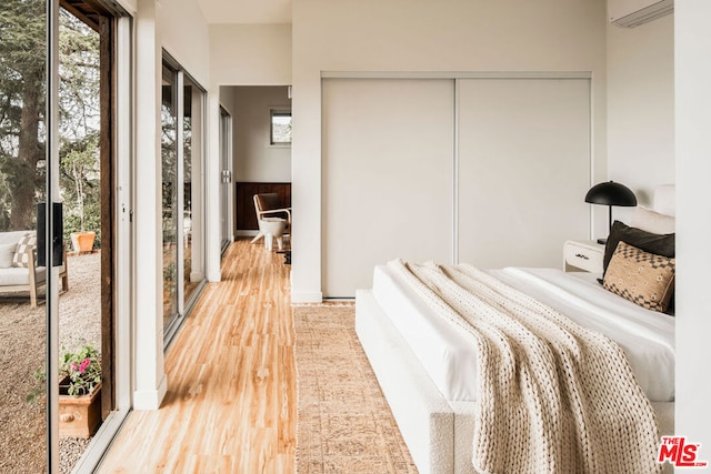 bedroom with a wall mounted AC and wood-type flooring