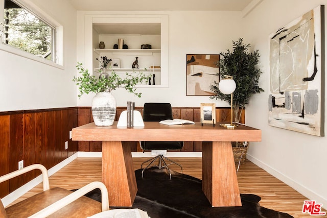 office featuring hardwood / wood-style flooring, built in desk, and wooden walls