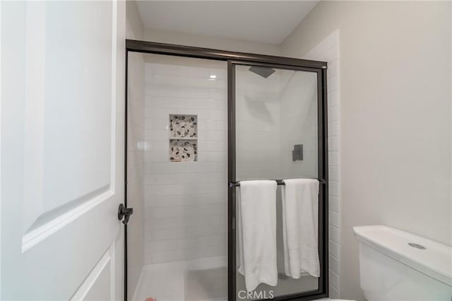 bathroom featuring toilet and an enclosed shower