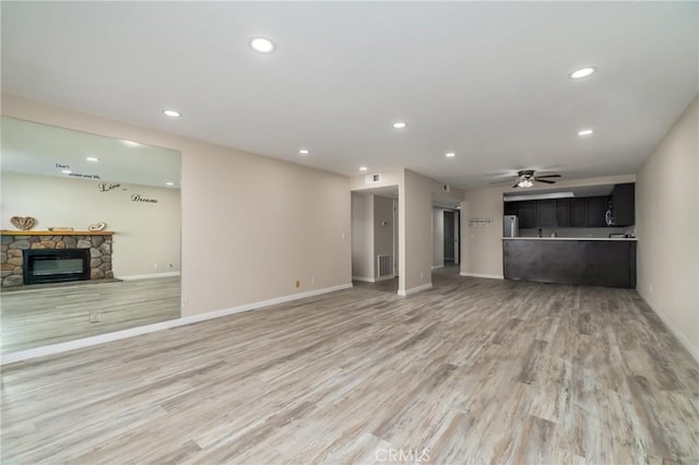 unfurnished living room with a fireplace, hardwood / wood-style flooring, and ceiling fan