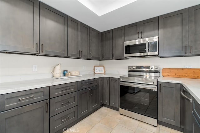 kitchen featuring light stone counters, light tile patterned flooring, and appliances with stainless steel finishes